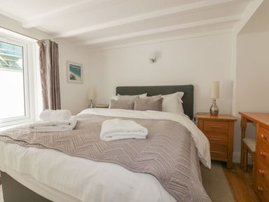 A bedroom with a bed a bedside table and a wooden desk at Blacksmiths Cottage in Crantock