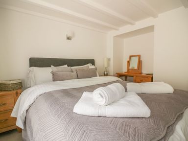 A bedroom with a made bed and towels on top at Blacksmiths Cottage in Crantock