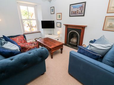 A living room with blue sofas a wooden coffee table a fireplace and a wall mounted TV at Pentira in Kuggar