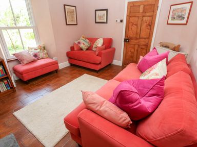 A room with red sofas and armchairs with pillows a wooden door and framed pictures on the walls at Pentira in Kuggar