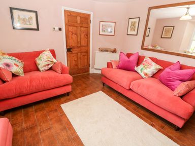 A living room with two red sofas and a white rug on a wooden floor at Pentira in Kuggar