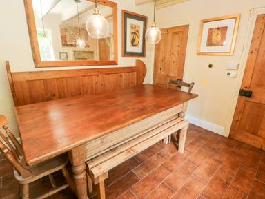 A wooden dining table with chairs and benches in a room with wooden doors and a large mirror at Pentira in Kuggar