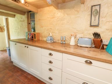 A kitchen counter with a kettle, toaster, knife block, spice containers, and utensils on top at Pentira in Kuggar