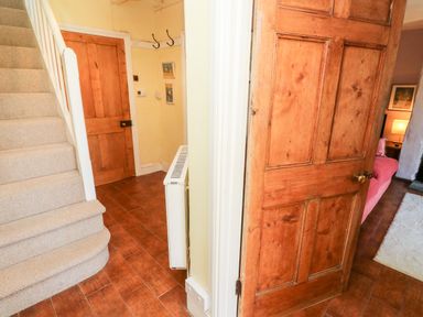 A hallway with carpeted stairs wooden doors a radiator and a glimpse of a room with a bed and lamp at Pentira in Kuggar