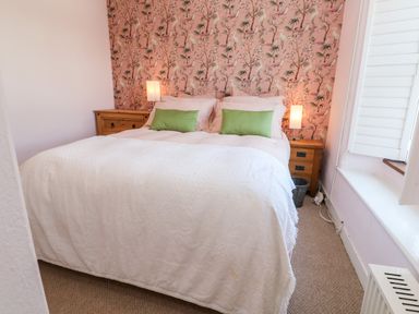 A bedroom with a double bed two wooden bedside tables with lamps and a window with shutters at Pentira in Kuggar
