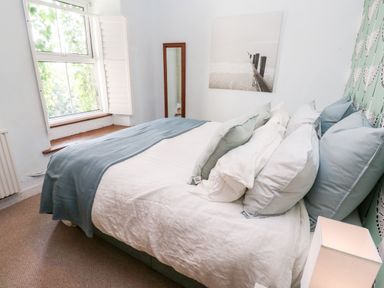 A bedroom with a double bed pillows a window a standing mirror and a wall picture at Pentira in Kuggar