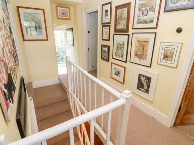 A hallway with carpeted stairs and framed pictures on the walls at Pentira in Kuggar