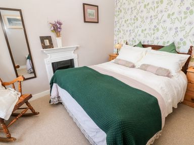 A bedroom with a bed covered with white and green bedding beside wooden nightstands and a fireplace at Pentira in Kuggar