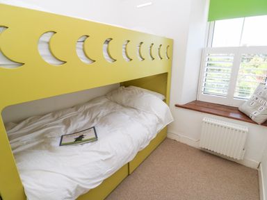 A bedroom with a yellow bunk bed and a window with green blind at Pentira in Kuggar
