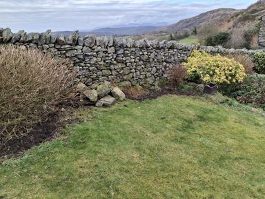 A garden with a stone wall and grassy area at Horse and Farrier Barn Newton in Cartmel near Cartmel