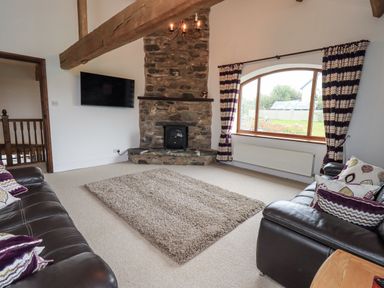 A living room with a fireplace and a sofa at Horse and Farrier Barn in Newton in Cartmel near Cartmel