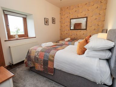 A bedroom with two beds and a window at Horse and Farrier Barn Newton in Cartmel near Cartmel