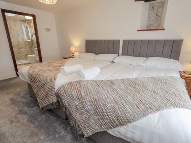 A bedroom with two beds and an ensuite bathroom at Horse and Farrier Barn in Newton in Cartmel near Cartmel