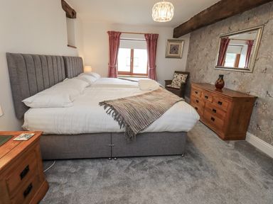 A bedroom with a bed and dresser at Horse and Farrier Barn, Newton in Cartmel near Cartmel