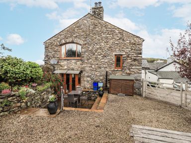 A stone house exterior with plants and a gravel area at Horse and Farrier Barn, Newton in Cartmel near Cartmel