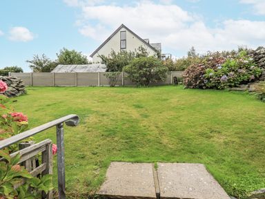 A garden with flower shrubs and a house in the background at Horse and Farrier Barn Newton in Cartmel near Cartmel
