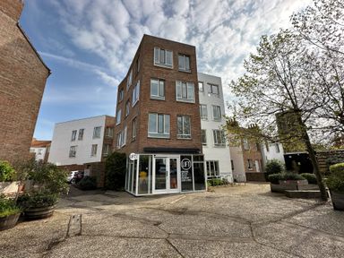 A courtyard with a multi-story brick and white building with a shop named LIFT in Southwold
