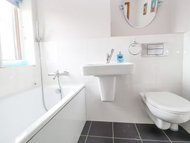 A bathroom with a bathtub shower sink mirror toilet and a window at 23 Tibbys Way in Southwold