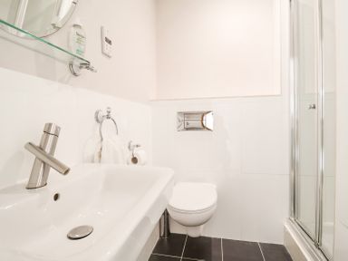 A bathroom with a sink faucet toilet towel rail and a glass shower at 23 Tibby's Way Southwold