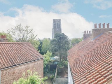 View of brick houses with tiled roofs trees and a tall church tower in the background at 23 Tibbys Way in Southwold