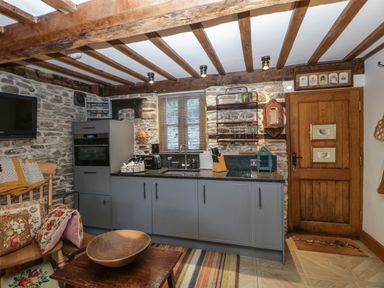 A kitchen with stone walls wooden beams gray cabinets and a wooden door at Hoarders Cottage in Hay-On-Wye