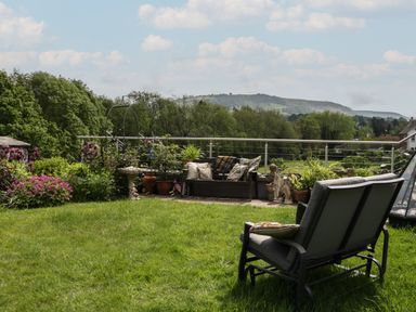 A garden with seating and potted plants overlooking hills at Hoarders Cottage in Hay-On-Wye