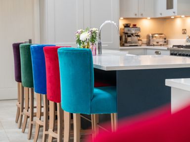 A kitchen island with colorful bar stools and flowers on the counter at The Stables in Wheatley