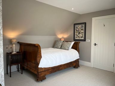 A bedroom with a wooden bed and side table with lamp at The Stables in Wheatley