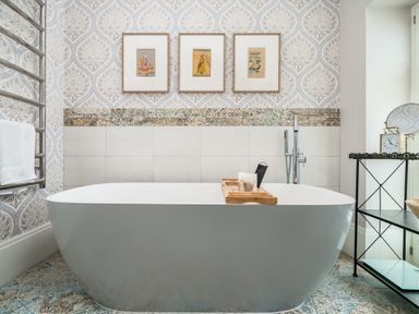 A bathroom with a freestanding bathtub and framed artworks on the wall at The Stables in Wheatley