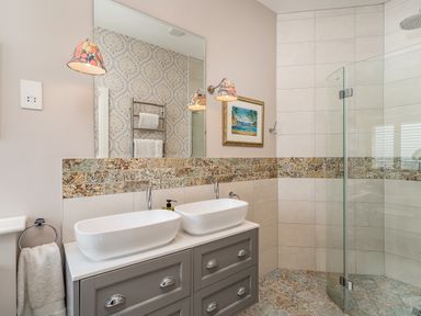 A bathroom with two white sinks on a gray cabinet and a glass shower enclosure at The Stables in Wheatley