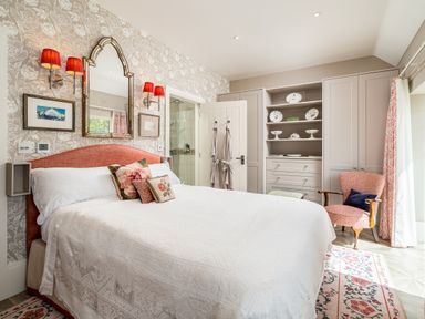A bedroom with a bed pillows mirror armchair and built in shelves at The Stables in Wheatley