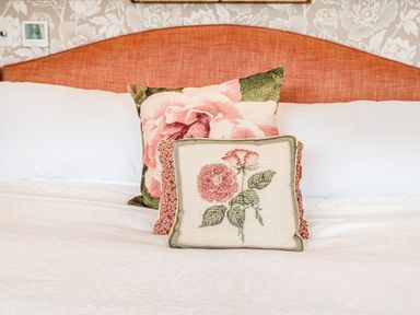 A bed with an orange headboard and two floral pillows at The Stables in Wheatley