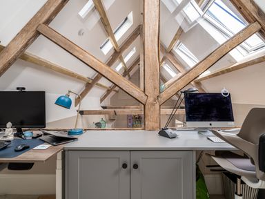 An office space with two computer desks a blue lamp and wooden beams on the ceiling at The Stables in Wheatley