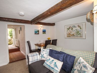 A living room with a sofa and dining table with chairs at Dormouse Cottage in Burton Bradstock