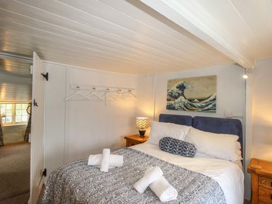 A bedroom with a double bed two bedside tables a lamp and hangers on the wall at Dormouse Cottage in Burton Bradstock