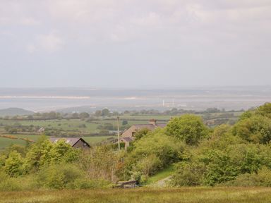 A rural landscape with houses, green fields, trees, and distant hills at Gwel Y Mor Nasareth near Caernarfon