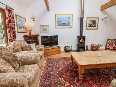 A living room with patterned sofas a wooden coffee table and a wood burning stove at Bridge Cottage in Dalwood
