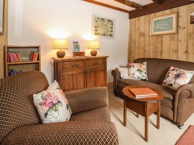 A sitting room with two couches a wooden cabinet with two lamps and a small wooden table at Bridge Cottage in Dalwood