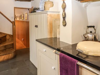 A kitchen corner with wooden stairs and a kettle on a stove at Bridge Cottage in Dalwood