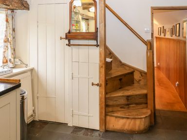 A wooden staircase next to white paneled walls and a hallway with framed pictures at Bridge Cottage in Dalwood