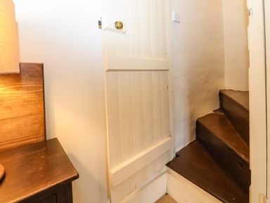 A small wooden staircase beside a white wooden door and a wooden table with a lamp at Bridge Cottage in Dalwood