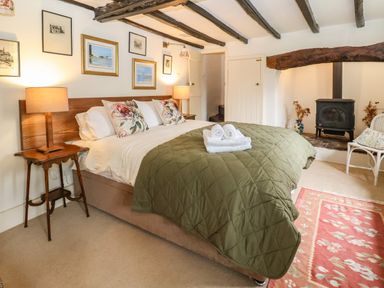 A bedroom with a bed covered in green quilt and floral pillows beside wooden side tables and lamps at Bridge Cottage in Dalwood