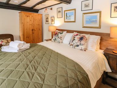 A bedroom with a large bed with floral pillows and green quilt at Bridge Cottage in Dalwood