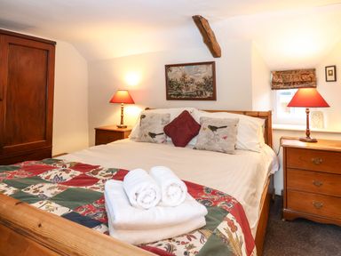A bedroom with a wooden bed a quilt and bedside lamps at Bridge Cottage in Dalwood