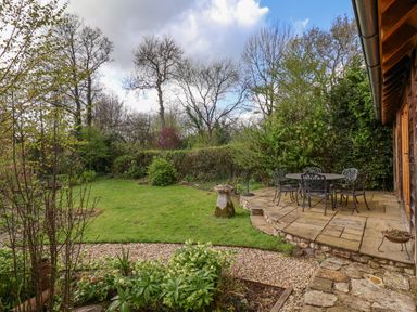 An outdoor garden with a patio table and chairs a lawn and trees at Bridge Cottage in Dalwood