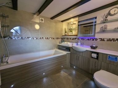 A bathroom with a bathtub shower sink and toilet at The Dairy at Brackenthwaite Farm in Arnside