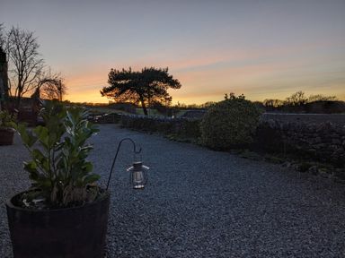 A gravel driveway with a planter and lantern at sunset at The Dairy at Brackenthwaite Farm in Arnside
