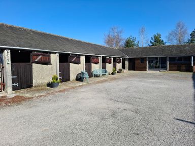 An outdoor courtyard with stable doors, benches, and potted plants at The Dairy at Brackenthwaite Farm in Arnside