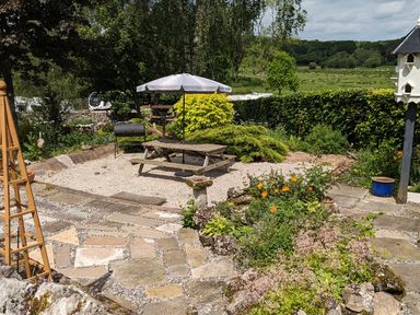 A garden area with a picnic table and umbrella surrounded by plants and flowers at The Dairy at Brackenthwaite Farm in Arnside
