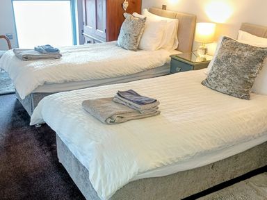 A bedroom with two beds and a bedside table at The Dairy at Brackenthwaite Farm in Arnside